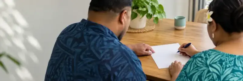 Two people sitting at a table filling in a form.