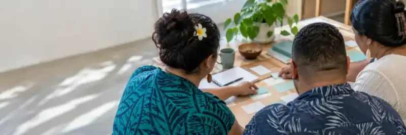 Three people working together around a table with notes and cards.